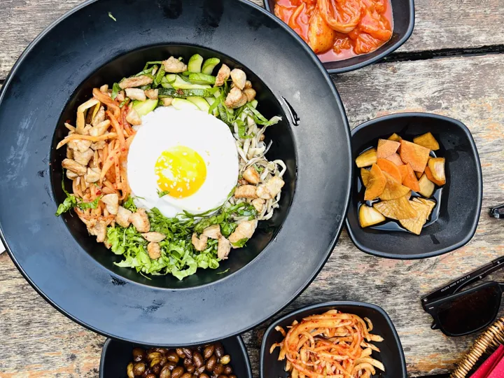 A bowl of bibimbap topped with vegetables and a fried egg