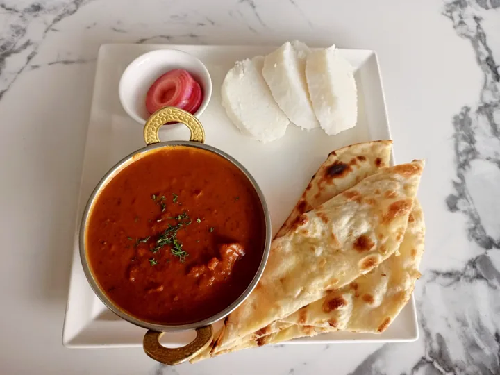 A bowl of rich red curry served with folded naan bread