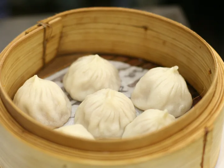 Steamed dumplings resting in a bamboo steamer basket