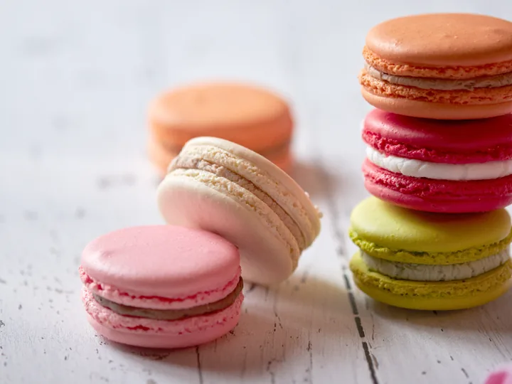 Stacked pastel macarons on a pale wooden surface