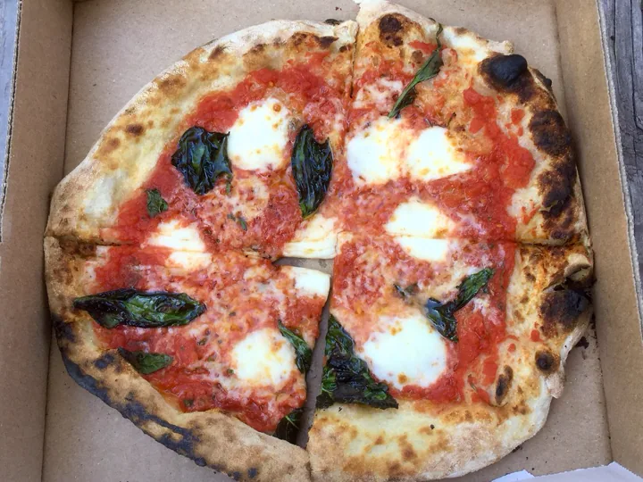 A wood-fired margherita pizza with basil and mozzarella