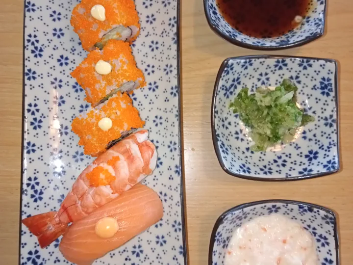 An assortment of nigiri sushi arranged on a patterned plate