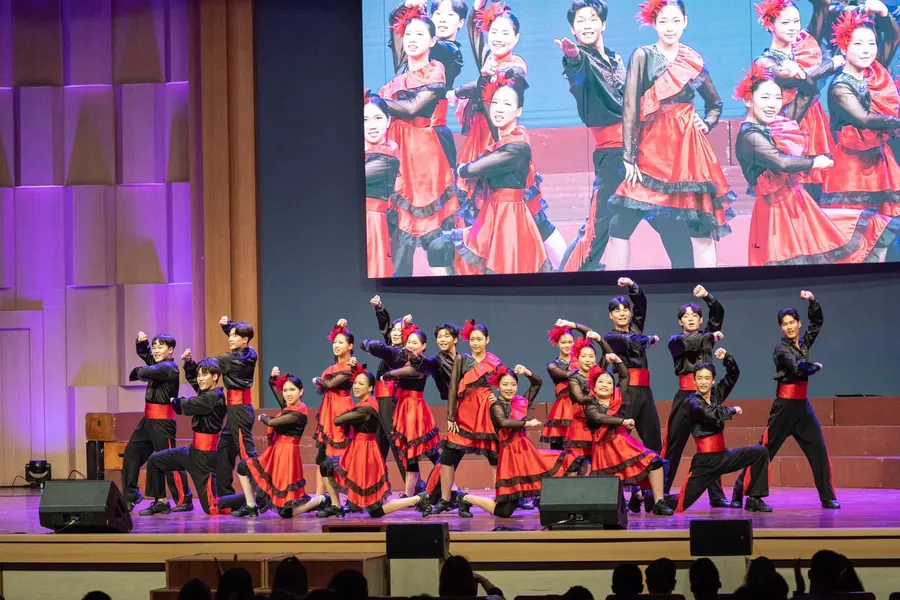 A dance troupe in red and black filling the main stage at the 2024 festival