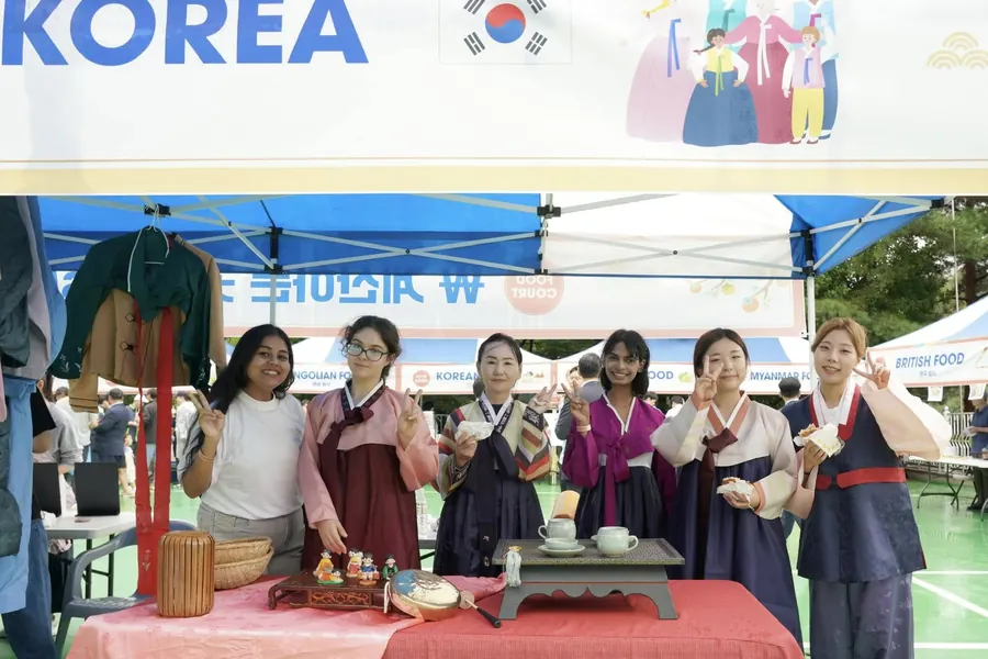 Hosts in hanbok serving tea to visitors at the Korea booth